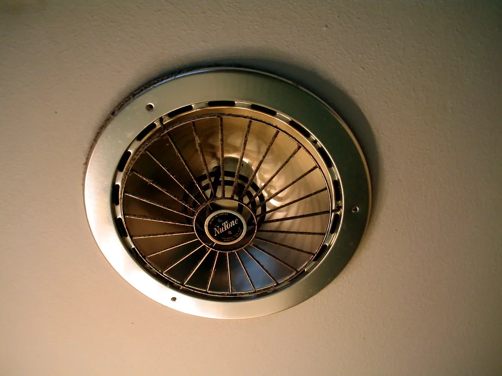 Close-up of a bathroom GFCI outlet beside a portable heater on tile