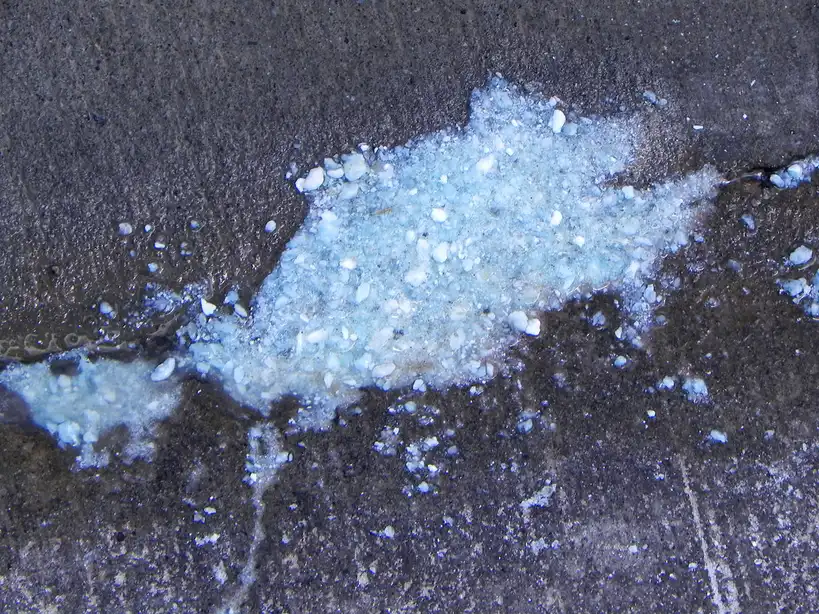 Hand draining sediment from a water heater valve into a bucket