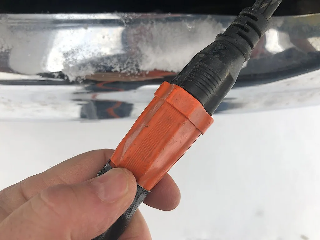 Close-up of a block heater cord plugged into a weatherproof outdoor power cover