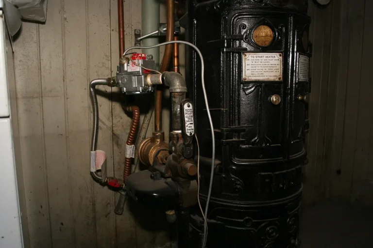 Plumber inspecting a residential water heater in a utility closet before replacement