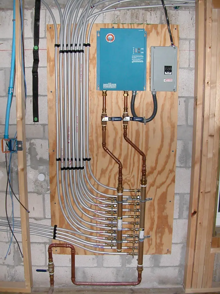 Hand turning the gas shutoff valve next to a water heater control area