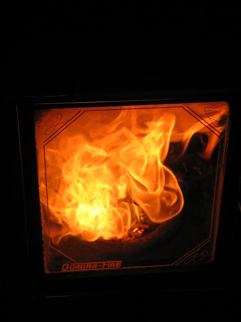 Hand pouring wood pellets into a pellet stove hopper