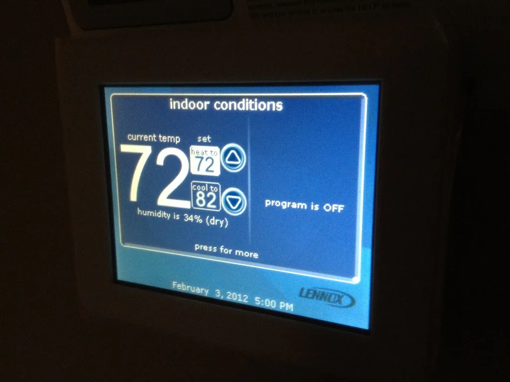 Homeowner and HVAC technician discussing a heat pump and furnace outside a house