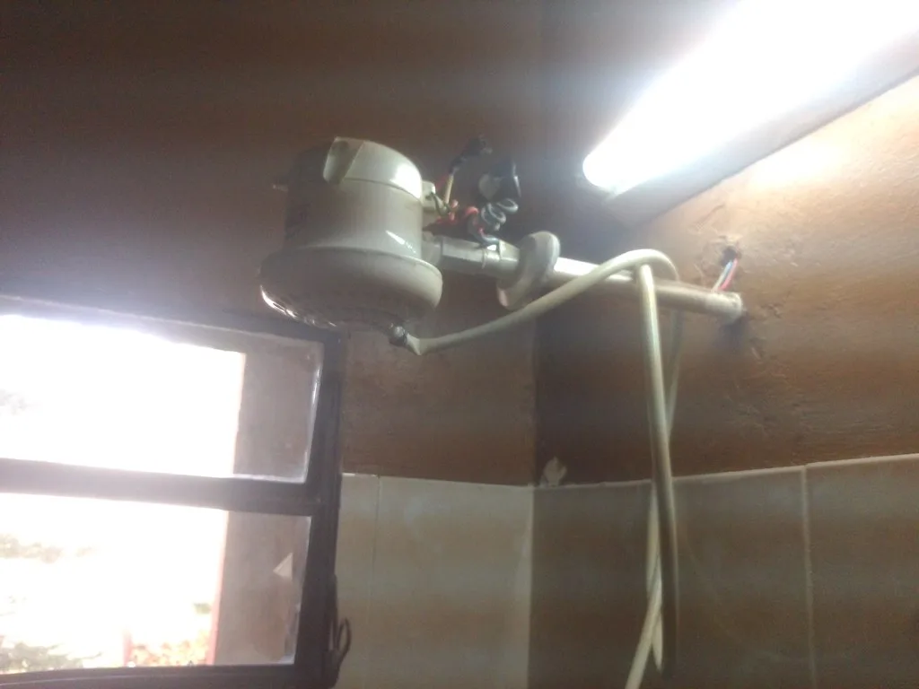 Homeowner inspecting a water heater beside a shutoff valve in a basement utility room
